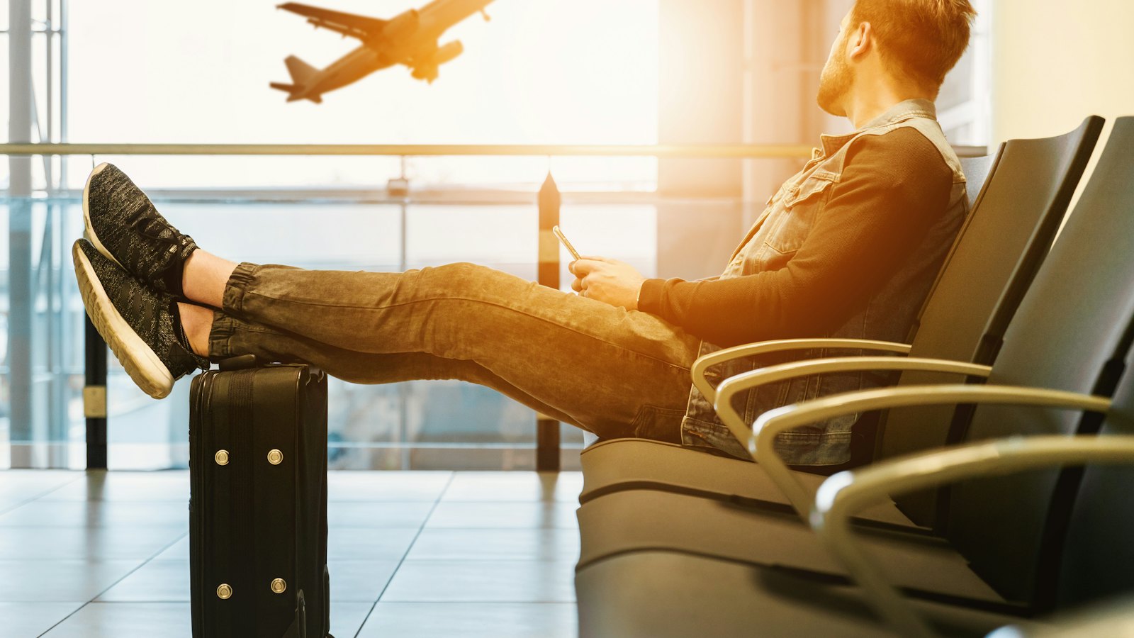 Traveller relaxing in an airport lounge as a plane takes off