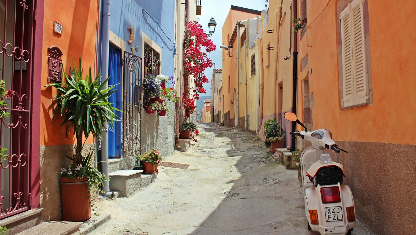 Colourful old-town street with a parked scooter
