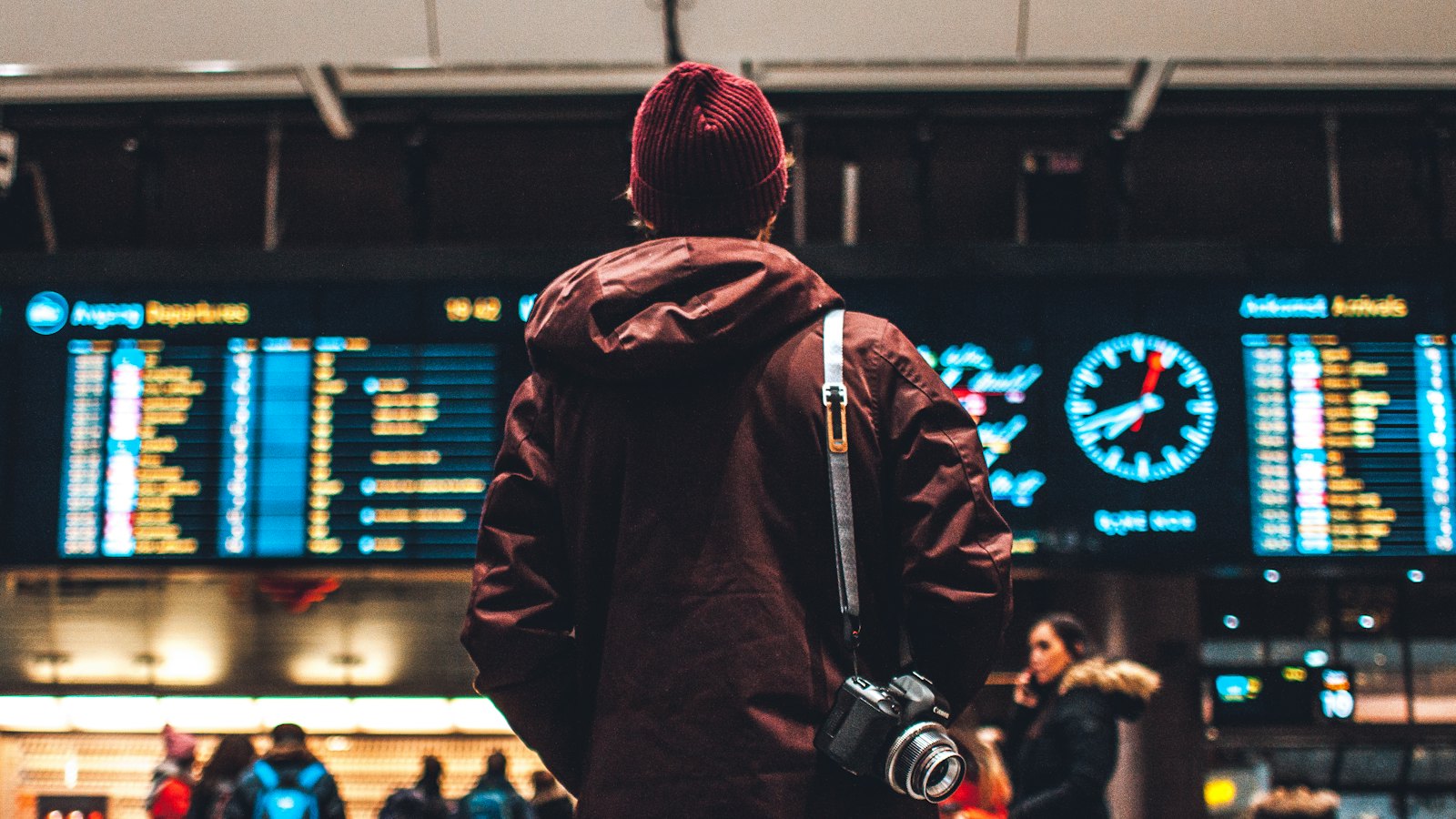Traveller with a camera looking up at an airport departures board
