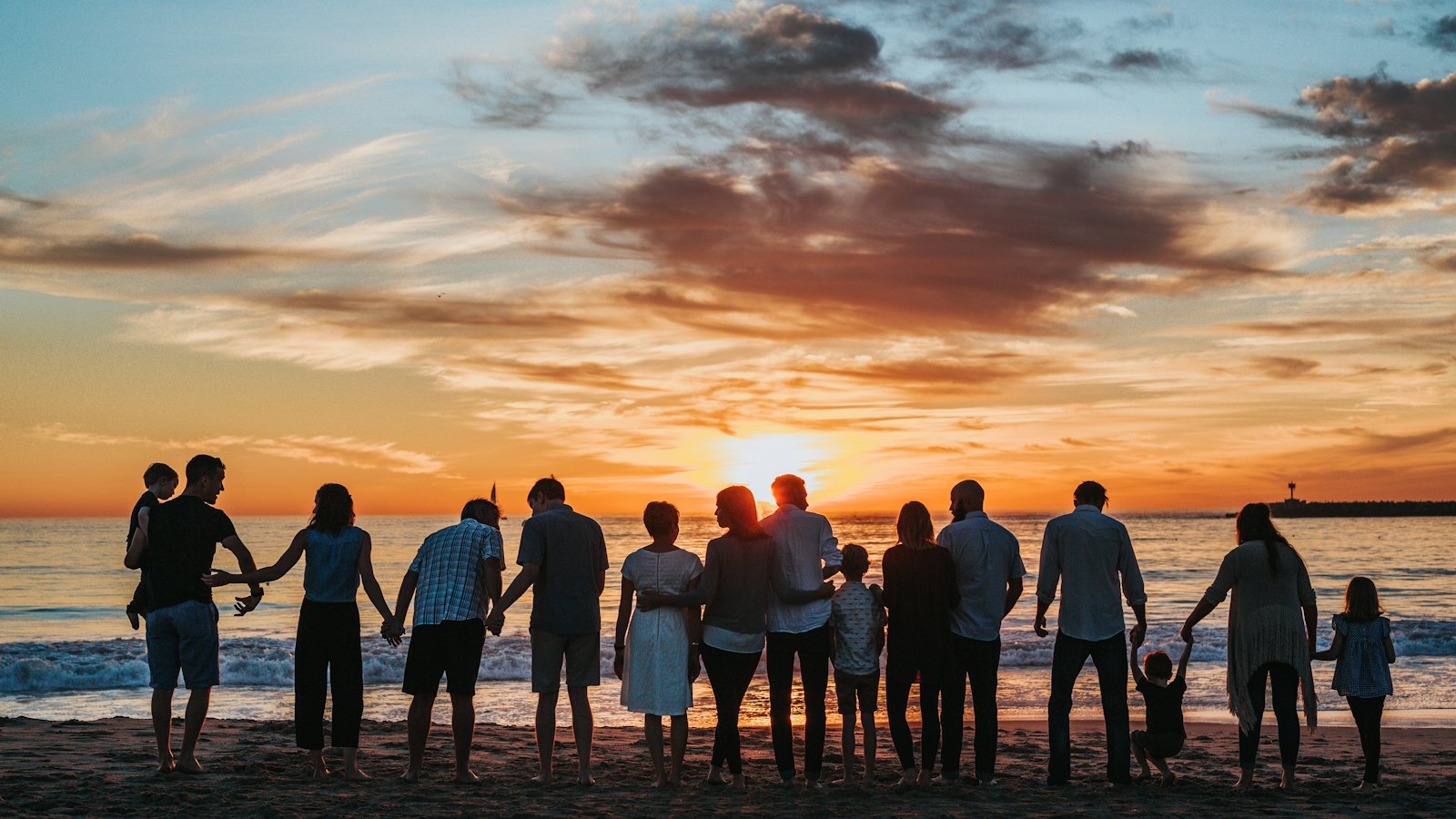 Large family holding hands on a beach at sunset