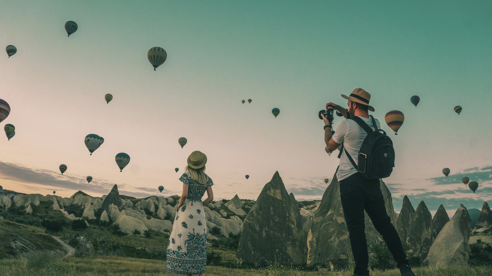 Travellers watching hot-air balloons rise over Cappadocia