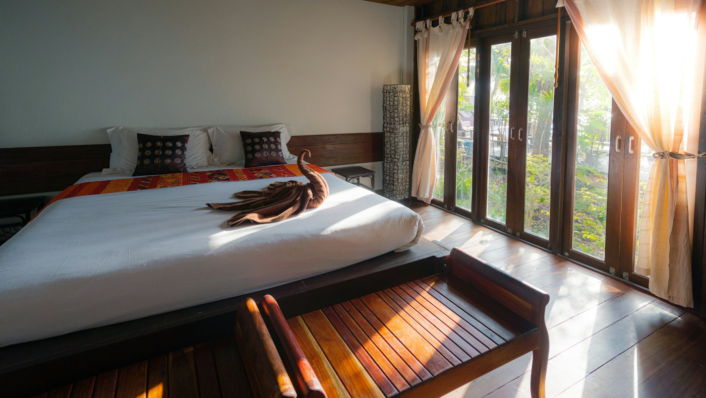 Bright hotel room with a made bed and tall windows