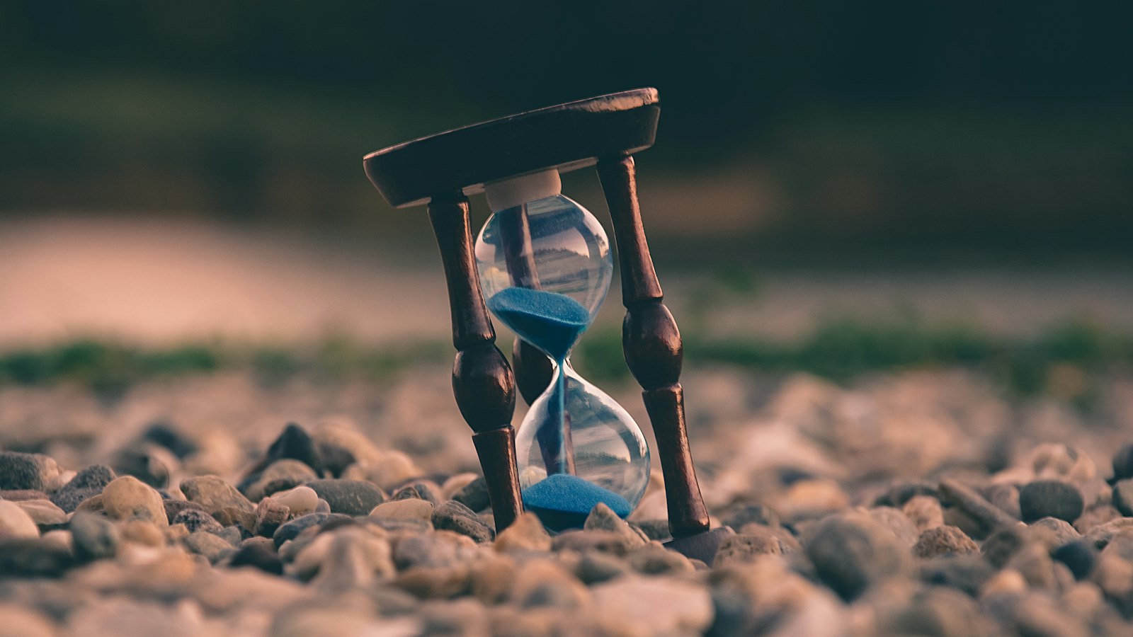 An hourglass standing on a pebble beach
