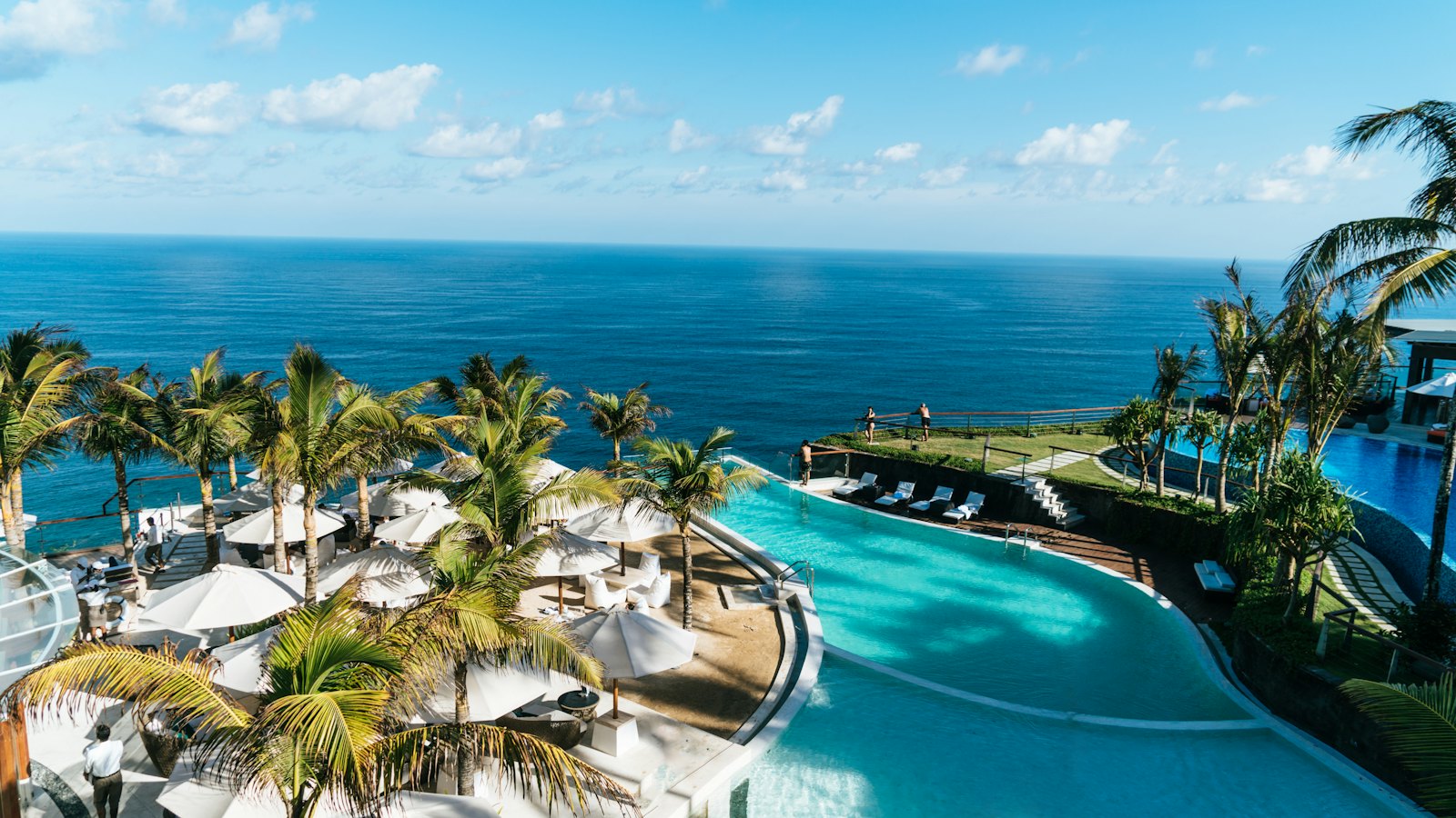 Resort infinity pool among palm trees overlooking the sea