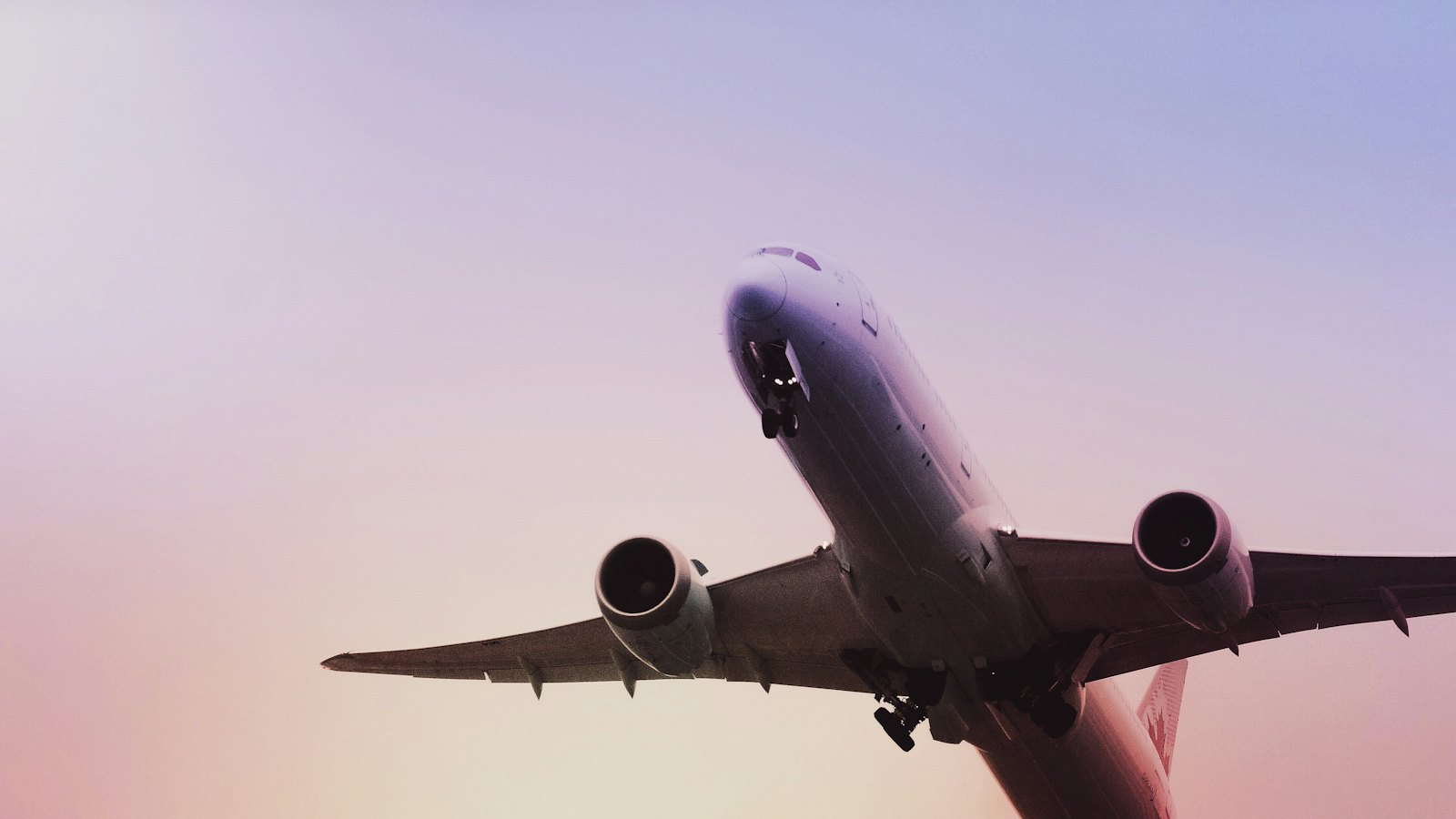 Passenger jet climbing into a pink evening sky