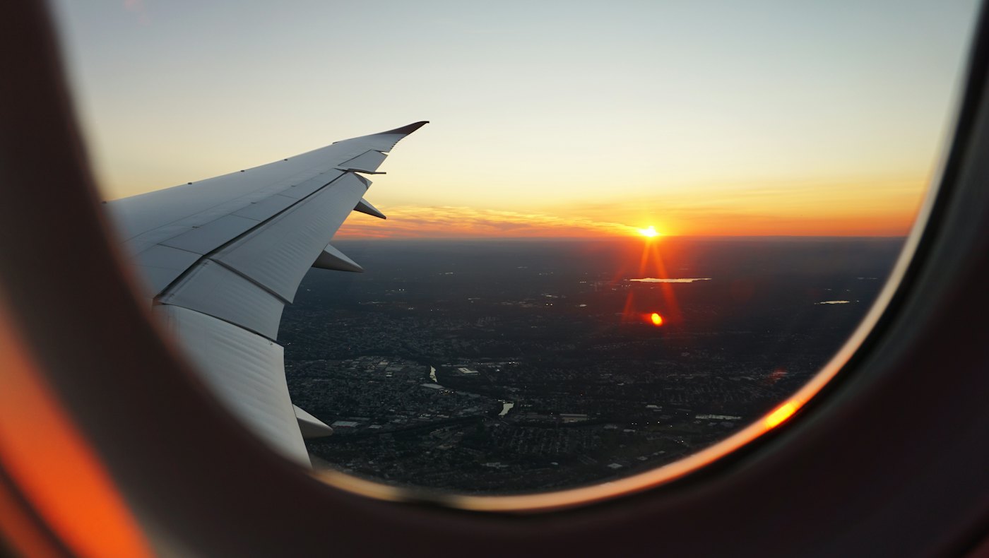 View of a sunset over a city from an aircraft window