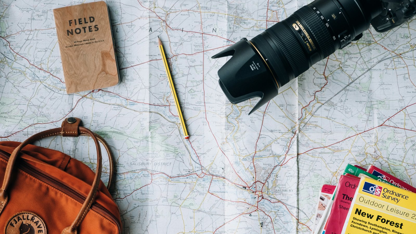 Map, notebook, camera and bag laid out for trip planning